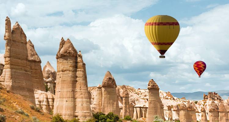 Montgolfières flottant au-dessus de formations rocheuses uniques.