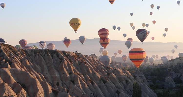 De nombreuses montgolfières au-dessus d'un paysage au lever du soleil.