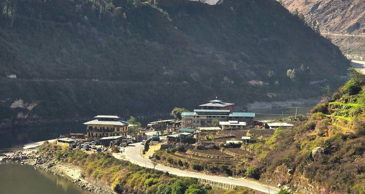 A town along a river with mountains in the background.