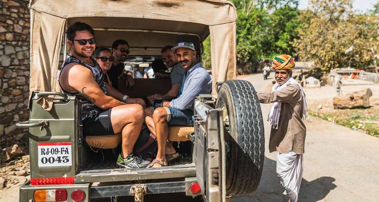 Des gens dans une jeep de safari à côté d'un homme local.