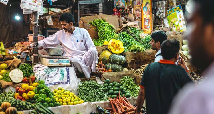 Scène de marché avec un vendeur qui vend des légumes.