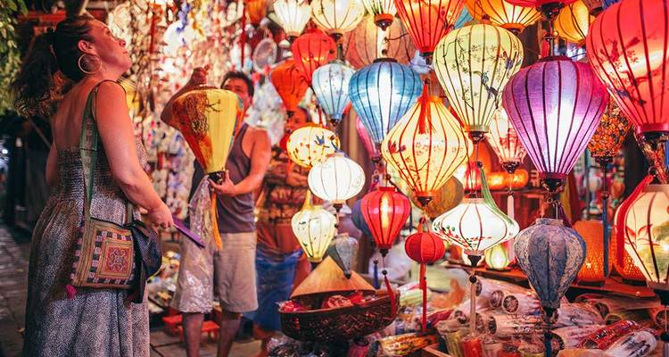 Personas admirando faroles coloridos en un mercado.