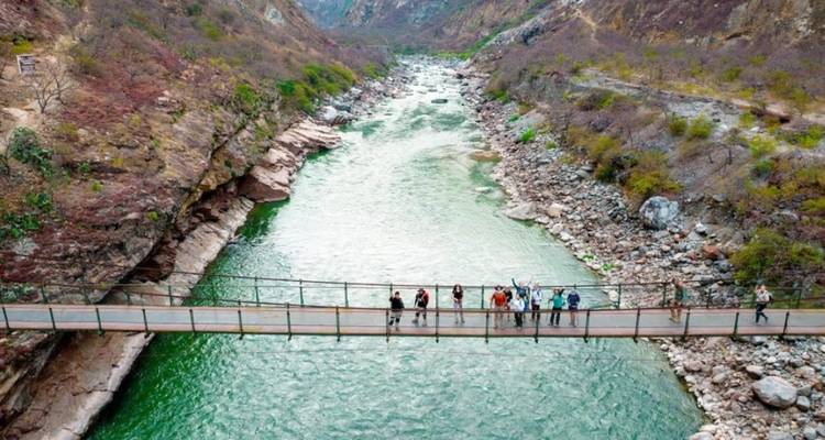 Personas en un puente colgante sobre un río.