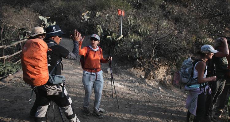 Excursionistas tomando un descanso en un sendero conversando y haciendo gestos con las manos.
