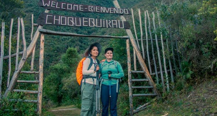 Dos mujeres paradas junto al letrero de entrada de Choquequirao.