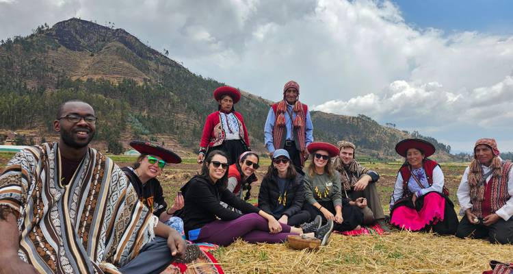 Groupe de personnes en vêtements traditionnels assises à l'extérieur.