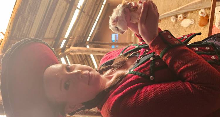 Femme tenant un cochon d'Inde dans une grange.