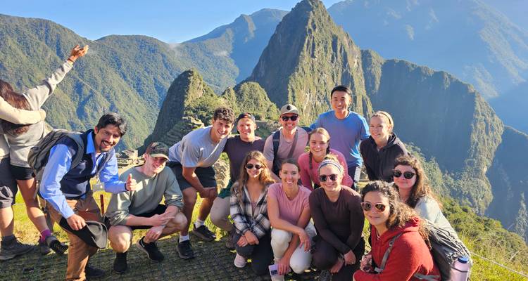 Groupe de personnes posant au Machu Picchu avec des montagnes en arrière-plan.