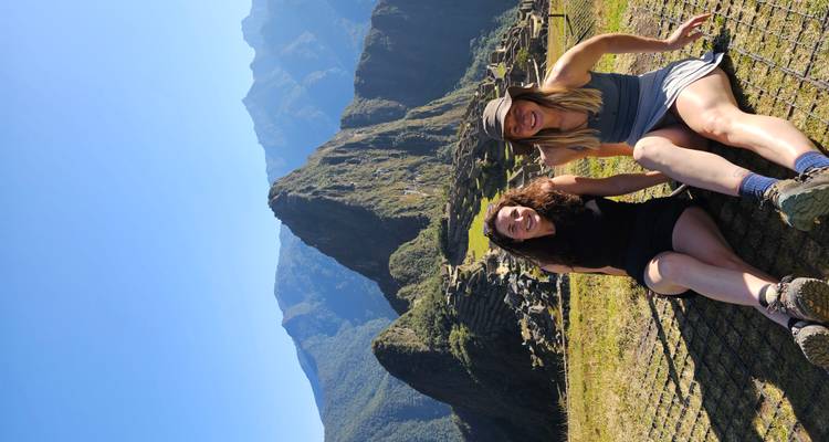 Deux personnes assises sur l'herbe avec le Machu Picchu en arrière-plan.