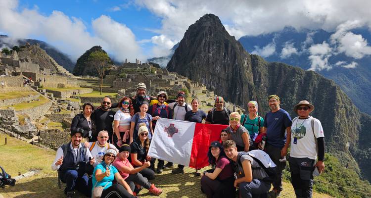 Grand groupe tenant un drapeau au Machu Picchu.
