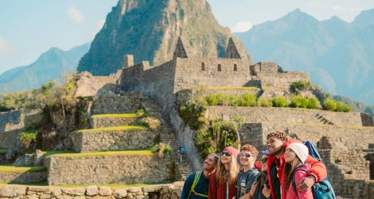 Glückliche Freundesgruppe, die mit Machu Picchu im Hintergrund posiert.