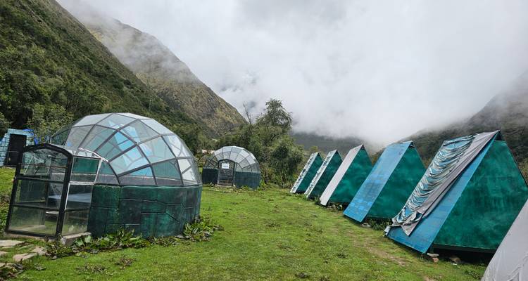 Reihe ungewöhnlicher Glaskuppeln und A-förmiger Strukturen in nebligen Bergen.