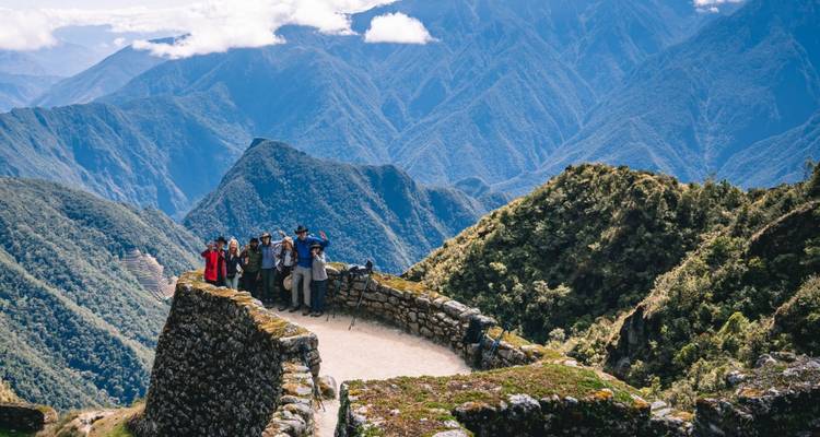 Grupo de pie en un sendero con vista a terreno montañoso.