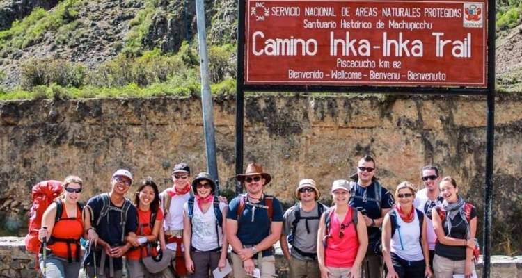 Grupo de personas al inicio del Sendero Inca paradas junto a un letrero de bienvenida.