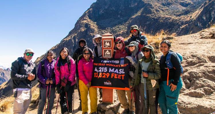 Grupo de excursionistas en el Paso de la Mujer Muerta con un letrero.