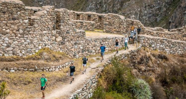 Excursionistas caminando entre antiguas ruinas de piedra.