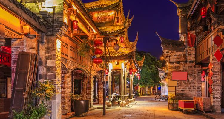 Scène de rue chinoise traditionnelle la nuit avec des lumières colorées.