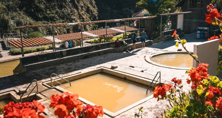 Personas relajándose junto a baños termales en una zona montañosa.