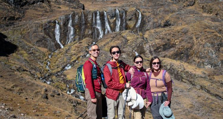Grupo de excursionistas posando frente a una cascada.