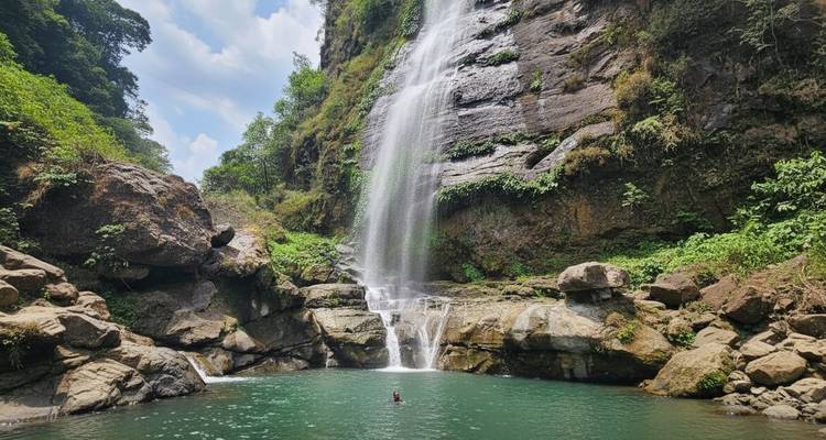 Waterfall cascading into a pool with a swimmer visible.