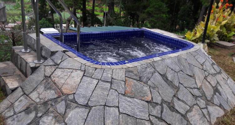 Outdoor-Jacuzzi mit Steinumrandung in natürlicher Umgebung.