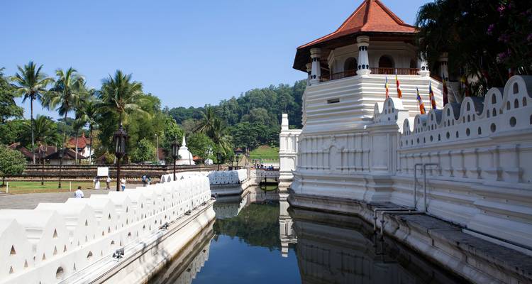 Weißes Tempelgebäude mit rotem Dach und Spiegelung im Wasser.