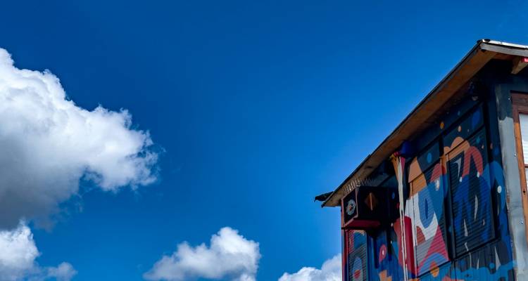 Bâtiment partiel avec graffitis vibrants sous un ciel bleu.