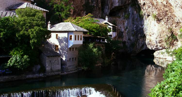 Cascade et bâtiments historiques au bord d'une rivière avec des falaises rocheuses à Blagaj, Bosnie.