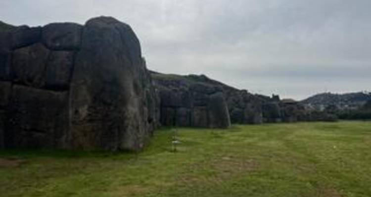Grands murs de pierre bordant un champ d'herbe verte.