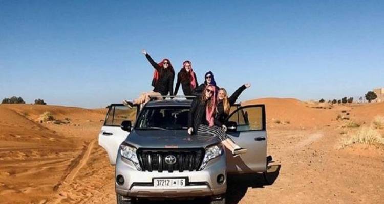 Groupe d'amis posant avec un véhicule tout-terrain dans un désert.