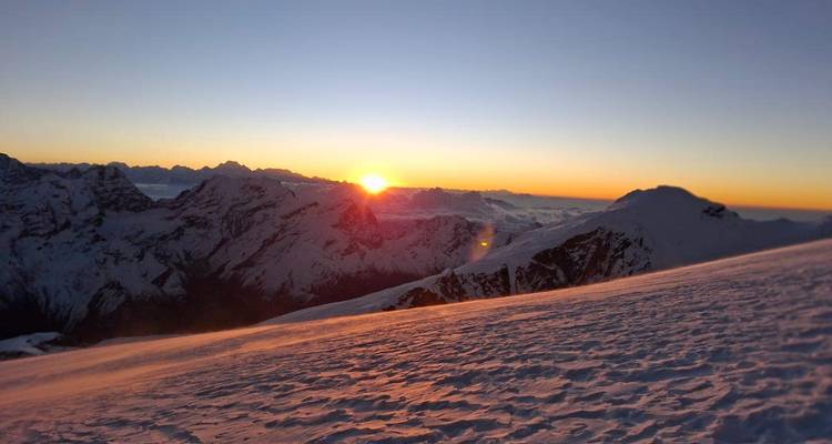 Un magnifique lever de soleil projetant une lumière chaude sur les pics enneigés de l'Himalaya et un champ de neige immaculé