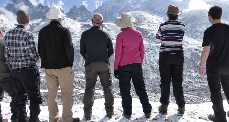 Un groupe de randonneurs photographiant des montagnes enneigées.