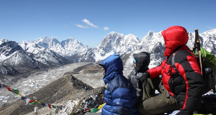 Groupe de personnes assises en tenue de neige admirant la vue sur les montagnes.