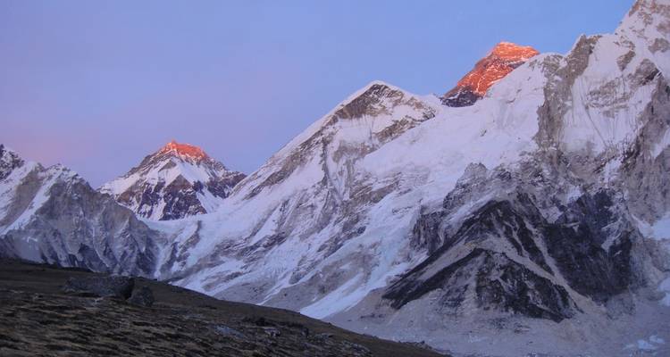 Pics montagneux enneigés au coucher du soleil, la lumière chaude atteignant les sommets.