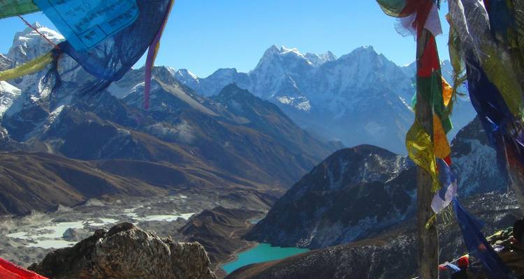 Une vue imprenable sur les montagnes avec des drapeaux colorés et un lac bleu serein en contrebas.