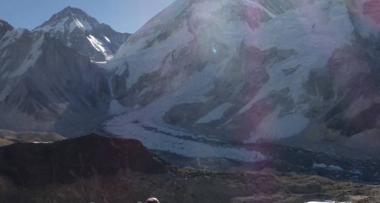 Une personne assise sur une crête avec une vue sur de vastes glaciers de montagne et de la glace.
