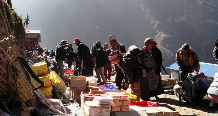 Un marché animé sur un sentier de montagne avec des gens qui interagissent avec les vendeurs.
