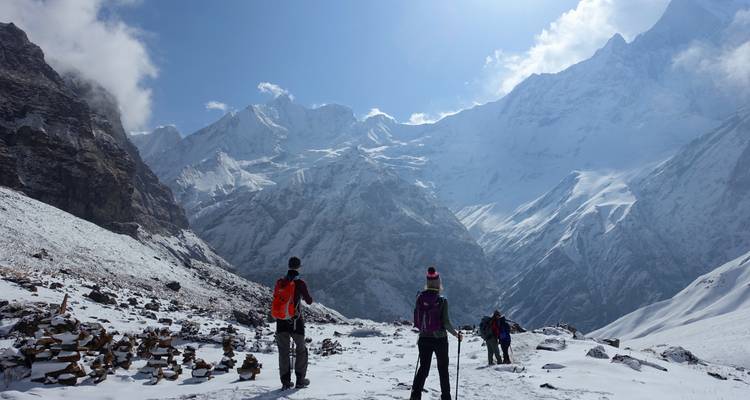 Senderistas vestidos con vibrantes ropas de invierno atraviesan un sendero nevado en el Himalaya.