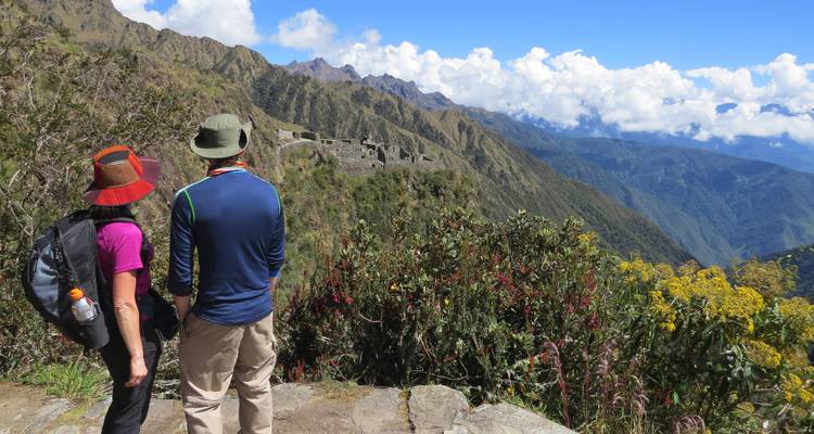 Dos personas frente a unas ruinas antiguas en una montaña.