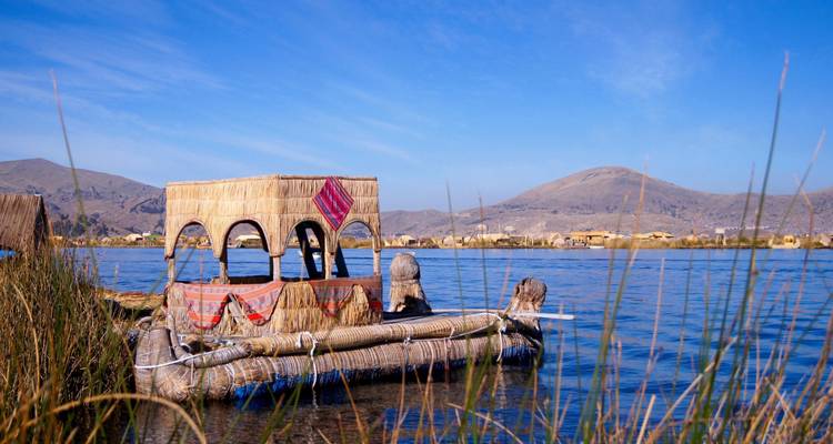 Barcas de juncos tradicionales en un lago sereno con colinas lejanas.