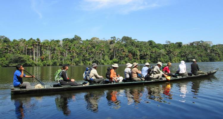 Turistas en canoa por un río tranquilo con un exuberante telón de fondo selvático.