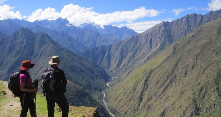 Dos excursionistas contemplando un impresionante valle con montañas.