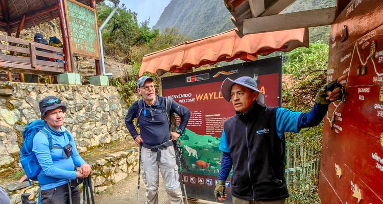 A trek guide briefs hikers at a trail information board in the Peruvian Andes.