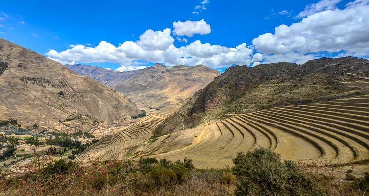 Expansive Inca terraces curve along a sunlit hillside in the Sacred Valley.
