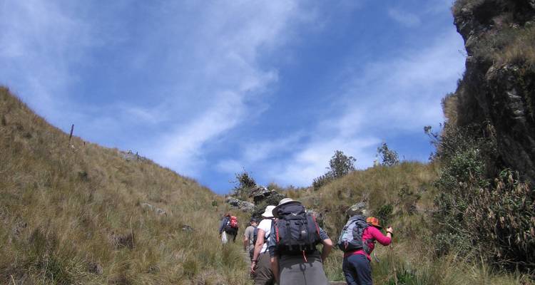 Grupo de excursionistas subiendo por un sendero de montaña bajo un cielo azul.