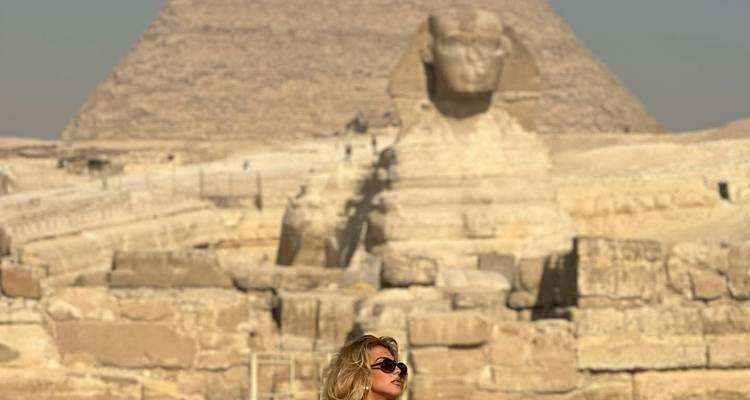 Una persona posando con la Esfinge y una pirámide al fondo.
