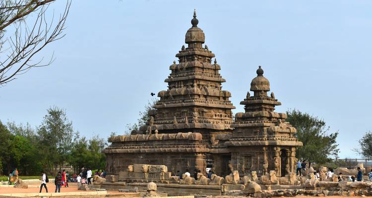 Temple ancien avec des gens autour, avec un ciel bleu en arrière-plan.