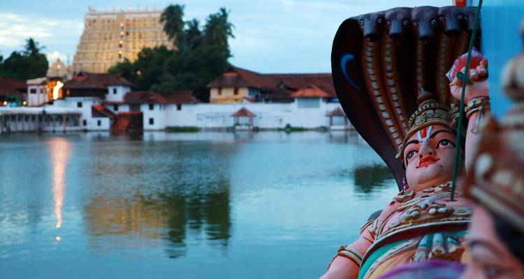 Une statue à côté d'un lac avec un bâtiment en arrière-plan.