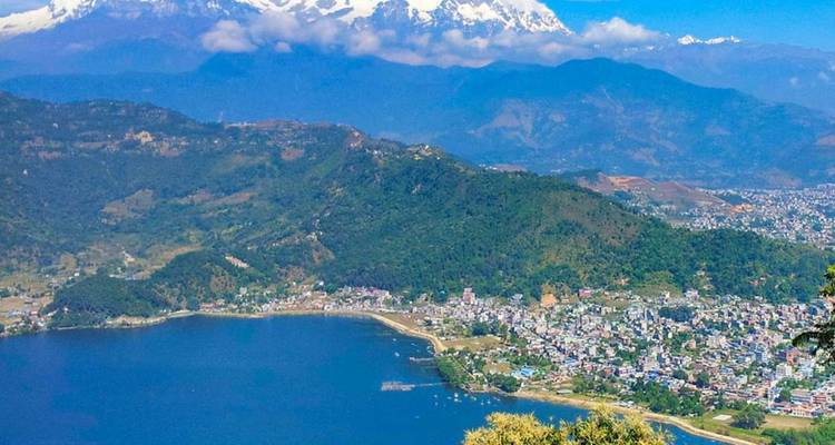 Vue aérienne d'une ville au bord d'un lac avec des montagnes à l'arrière-plan.