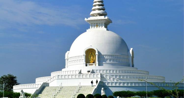 Un temple pagode blanc avec des statues dorées et des marches qui y mènent.